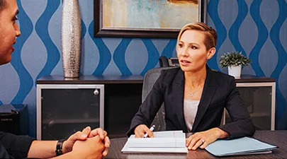 Photo of Deborah Gutierrez, founding Oxnard Employment Attorney of Gutierrez Law Firm, talking and consulting with client while sitting at her desk.